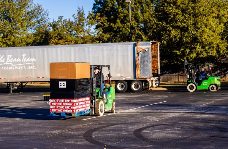 Forklift operators loading pallets onto a truck