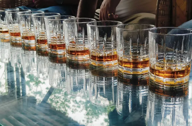 Line of whiskey glasses on a glass table