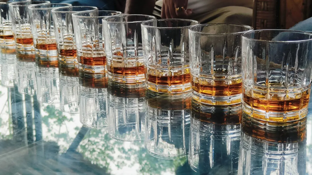 Line of whiskey glasses on a glass table